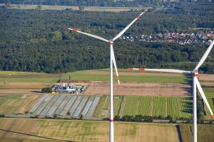 Windräder aus der Höhe gesehen mit Aussicht auf Wald und Ortschaft