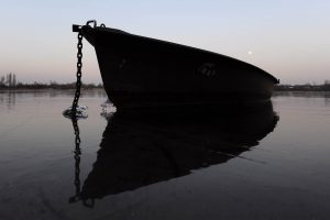 Verankertes Boot im Gegenlicht auf vereistem Wasser