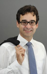 Portrait von Tilo in Hemd und Krawatte mit Sakko über der Schulter