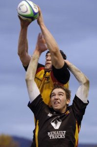 Rugbyspieler springen mit hochgereckten Armen nach oben, om den Ball zu fangen