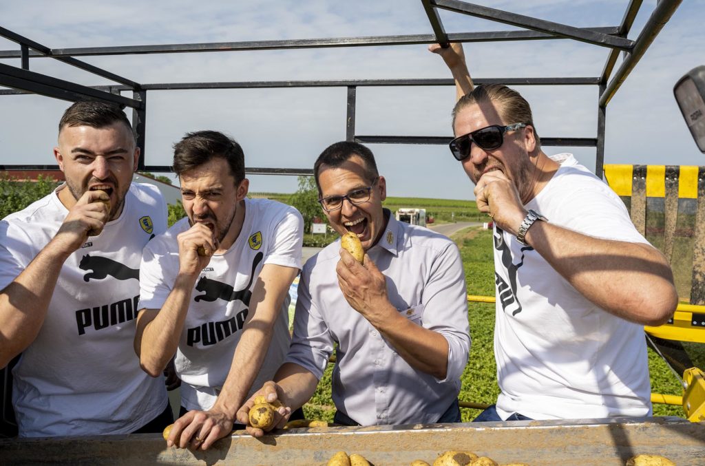 Jannnik Kohlbacher, Patrick Groetzki, Hartmut Magin, und Oliver Roggisch, auf der Rodemaschine tun so, als würden sie in die rohen Kartoffen beißen