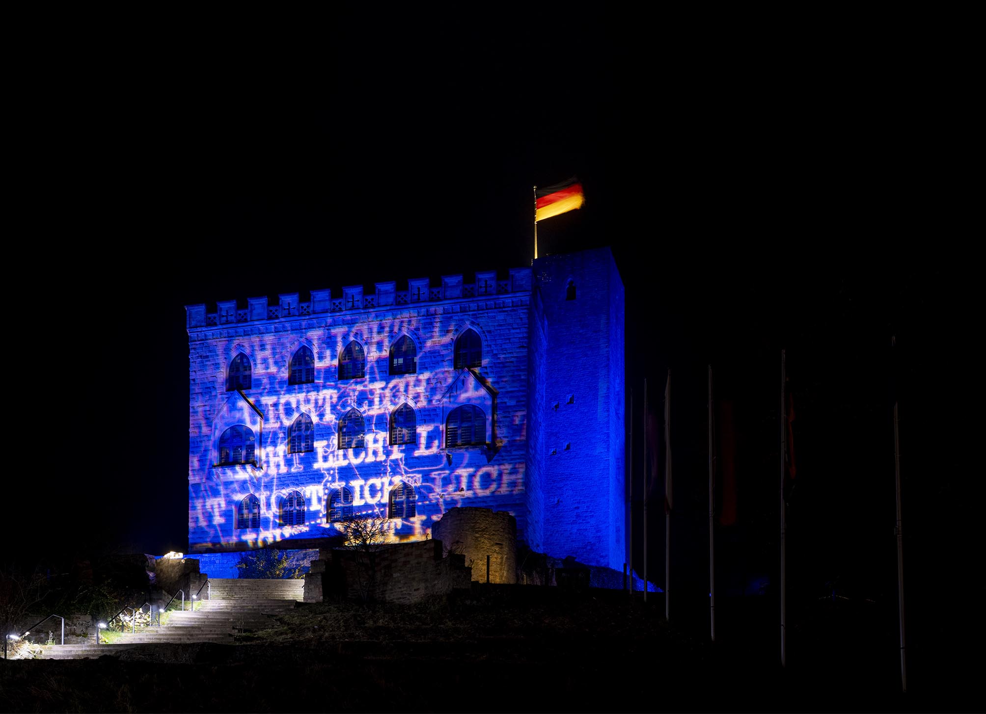 Hambacher Schloss bei Nacht mit blauer Beleuchtung, in der das Wort Licht zu lesen ist