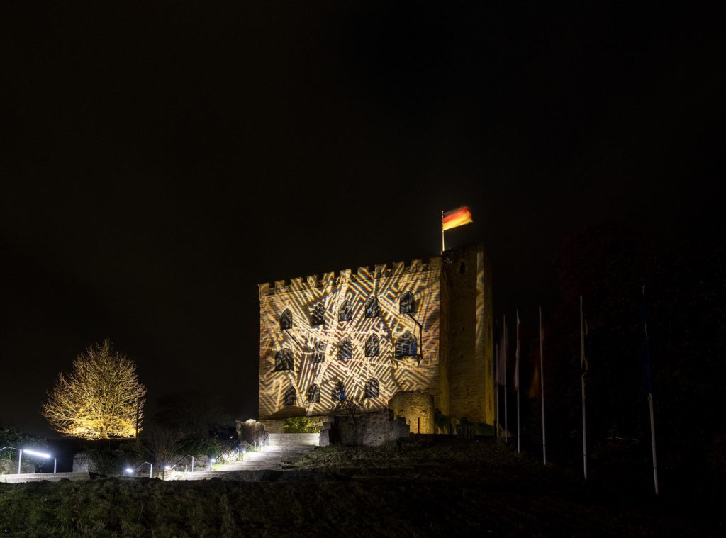 Hambacher Schloss bei Nacht mit überkreuzenden Labyrithmustern beleuchtet