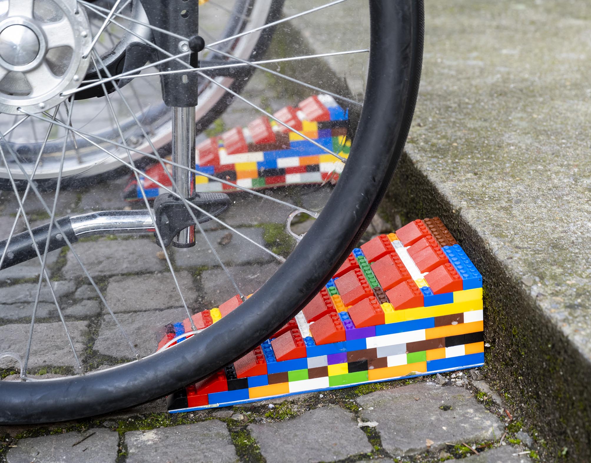 Großaufnahme einer Lego-Rampe unter einem Rollstuhlreifen