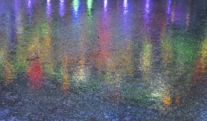 Bunte Lichter spiegeln sich auf dem von starkem Regen nassen Pflaster