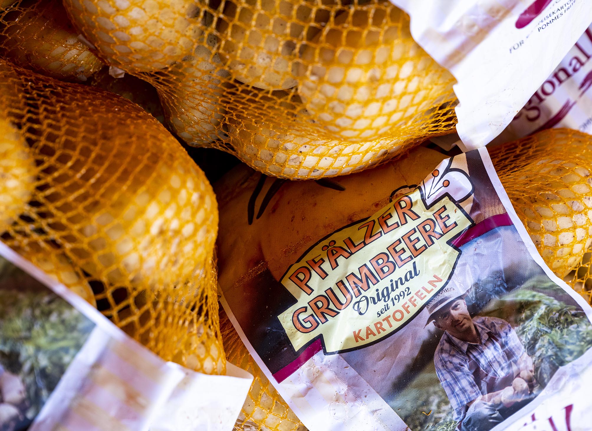 Frisch geerntete und in Säcken verpackte Kartoffeln mit dem Etikett Pfälzer Grumbeere Original seit 1992