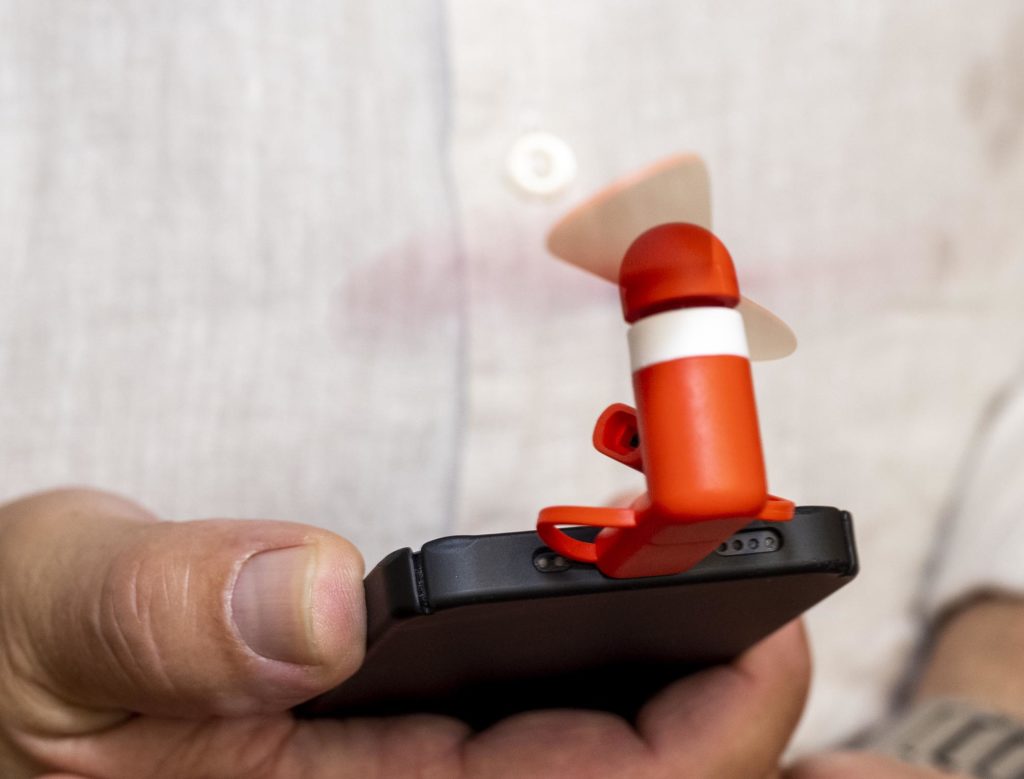 Hand hält Smartphone mit aufgetecktem Miniventilator