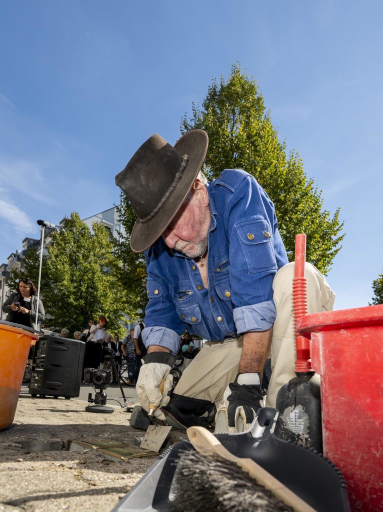 Initiator der Aktion, Künstler Gunter Demnig, beim Verlegen der Stolpersteine. Zuschauer im Hintergrund.