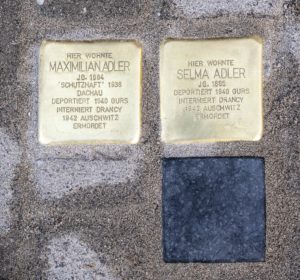 Vor dem Anwesen Wormser Straße 23 wurden 3 Steine für Maximilian Adler und Selma Adler und ein dritter Stein für den Sohn Eduard verlegt, wobei dessen Stein als Blindstein schwarz gehalten ist und keinen Schriftzug trägt, da er im 2. Weltkrieg einige Jahre in der Waffen-SS diente und seine Rolle in dieser Zeit schwierig zu beurteilen ist.