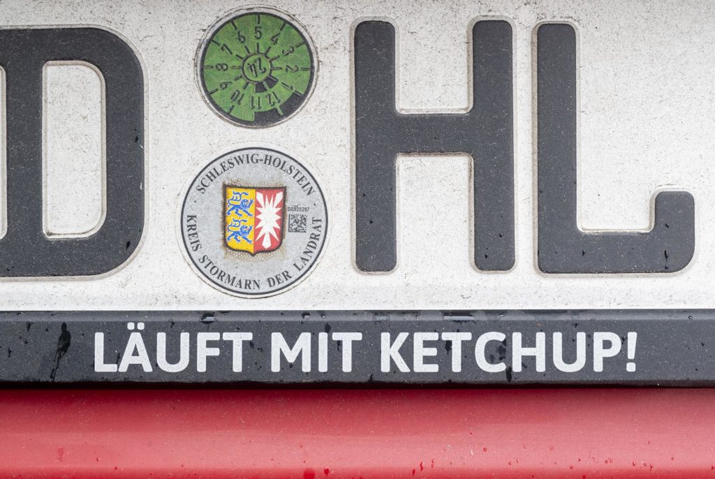 Großaufnahme eines Autokennzeichens, unter dem steht "Läuft mit Ketchup!"