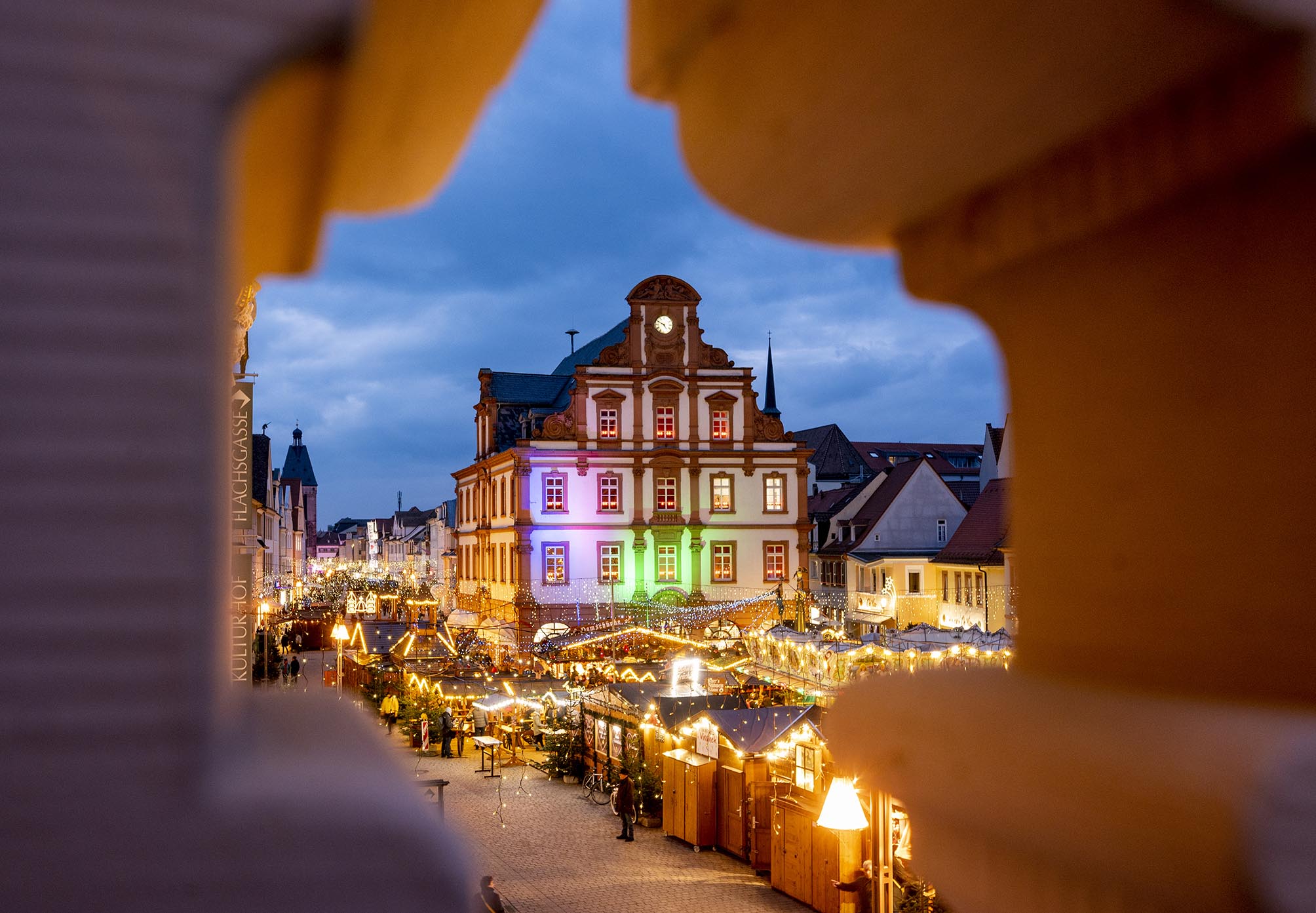 Blick auf die Alte Münze und den Weihnachtsmarkt durch eines der Ornamente in der Sandsteinballustrade des Rathaus-Balkons