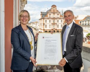 Oberbürgermeisterin Seiler mit Prof. Eichhorn und der Ehrenbürgerurkunde auf dem Balkon des Speyerer Rathauses mit Alter Münze im Hintergrund
