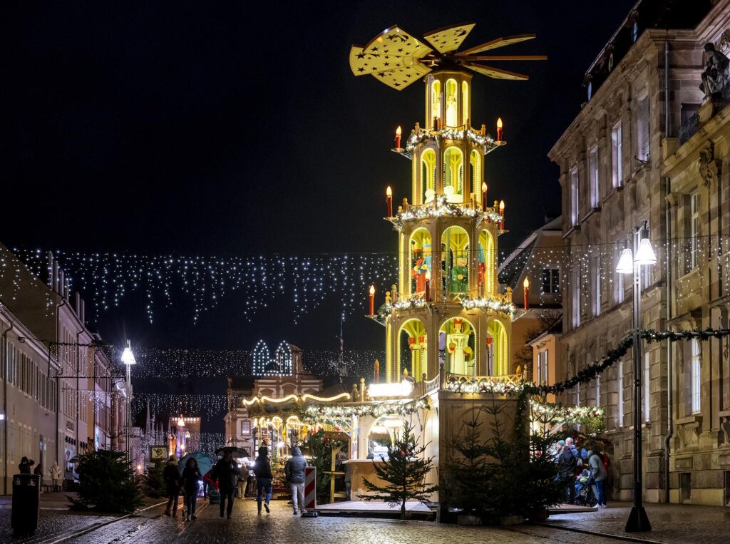 Nachtaufnahme der beleuchteten Weihnachtspyramide vor dem Speyerer Stadthaus rechts im Bild mit Blick die Maximilianstraße hinunter bis zum beleuchteten Altpörtel