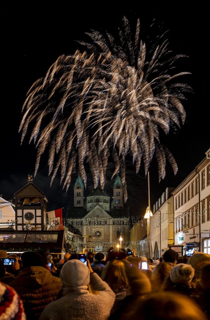 Viele Menschen, teils mit Smartphone, bestaunen von der Maximilianstraße aus das Feuerwerk über dem Dom. Hier riesiger goldener Regen.