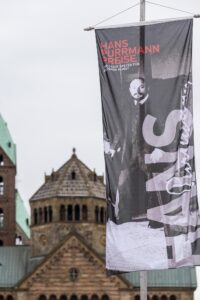 Die Speyerer Innenstadt ist auf der Maximilianstraße mit großen Fahnen, die Kunstwerke der vergangenen Purrmann-Preisträger zeigen, festlich geschmückt