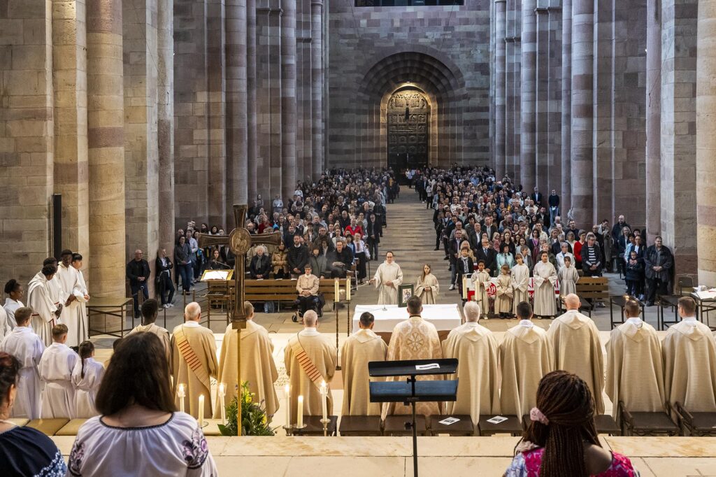 Pontifikalamt im Speyerer Dom fotografiert aus der Apsis ins Mittelschiff mit Priestern erc. von hinten und den Gläubigen in den Bänken von vorn