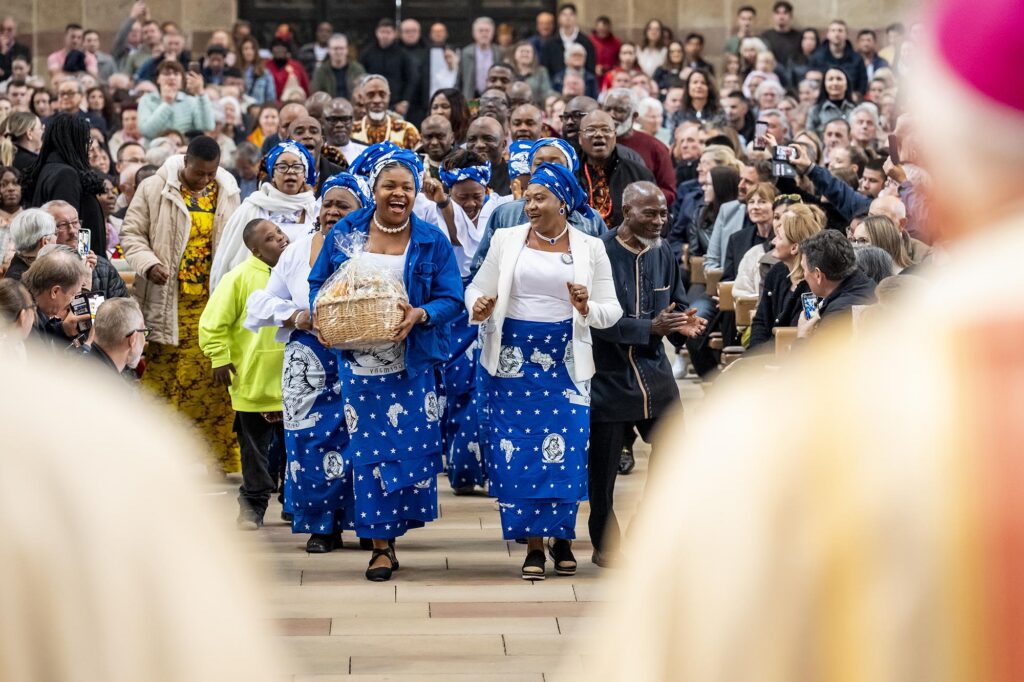 Die nigerianische Gemeinde( von vorn fotografiert) kommt singend und tanzend zur Gabenbereitung durch den Mittelgang zum Altar