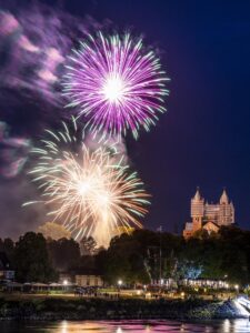 Zwei große Feuerwerksblumen in Pink und Gelb mit weißen Spitzen über dem Domgarten