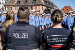 Zwei Polizisten von hinten. Auf ihren Westen steht „Mit Einsatz im Einsatz für Rheinland-Pfalz“