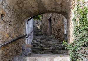 Malerischer Durchgang mit Torbogen zwischen zwei Sandsteinhäuserreihen über verwitterte Treppen den Berg hinauf