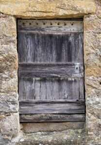 Verwitterte grobe Holztür in einer Sandsteinmauer