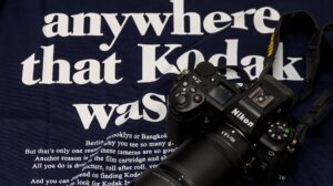 T-Shirt mit einem Schriftzug des ehemaligen Filmherstellers Kodak. Auf dem T-Shirt liegt eine Kamera Nikon Z6 III mit aufgesetztem Objektiv Z 1,8/50 S
