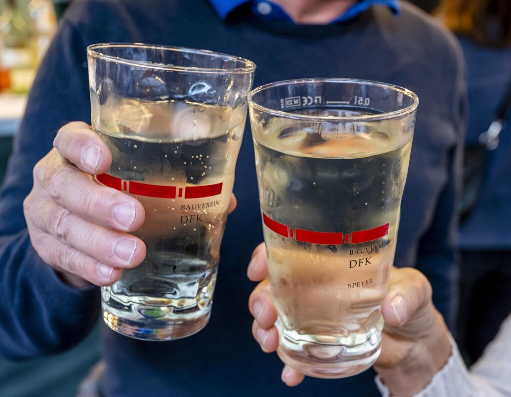 Großaufnahme zweier Hände mit Weinschorlegläsern beim Anstoßen