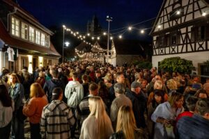 Viele Menschen in der nächtlich beleuchteten Salzgasse mit Blickrichtung Sonnenbrücke und Dom