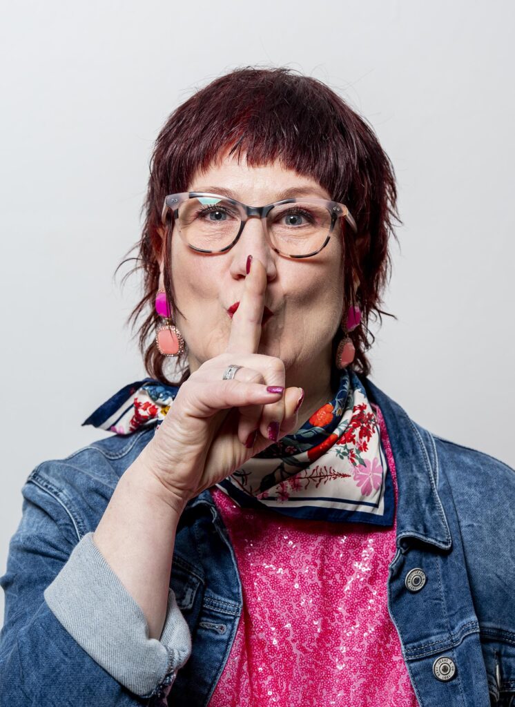 Bettina Hopfgarten mit Finger vor dem Mund, der signalisiert, zu flüstern