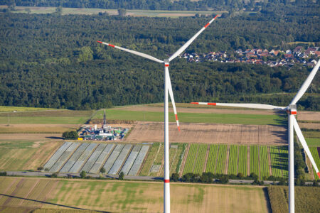 Windräder aus der Höhe gesehen mit Aussicht auf Wald und Ortschaft