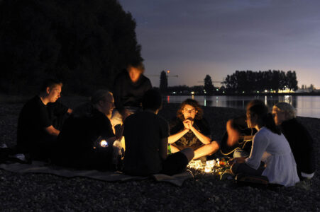 Jugendliche am nächtlichen Lagerfeuer am Rheinufer
