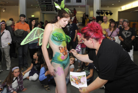 Zuschauer beobachten Frau, die bei einer anderen Bodypainting macht