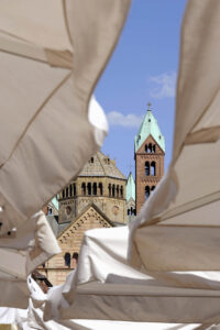 Türme des SPeerer Doms durch beige Sonnenschirme eines Cafés gesehen