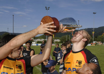 Rugbyspieler trinken nach dem Sieg aus dem Pokal